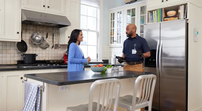 a homeowner speaks with an HVAC contractor in her kitchen