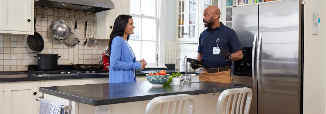 a homeowner speaks with an HVAC contractor in her kitchen