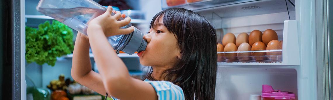 Kid drinking water from fridge